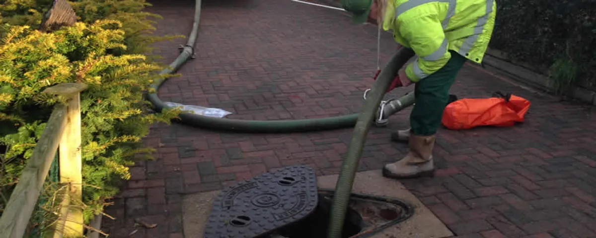 Septic tank cleaning technician servicing a septic tank with a vacuum hose in Allen, TX