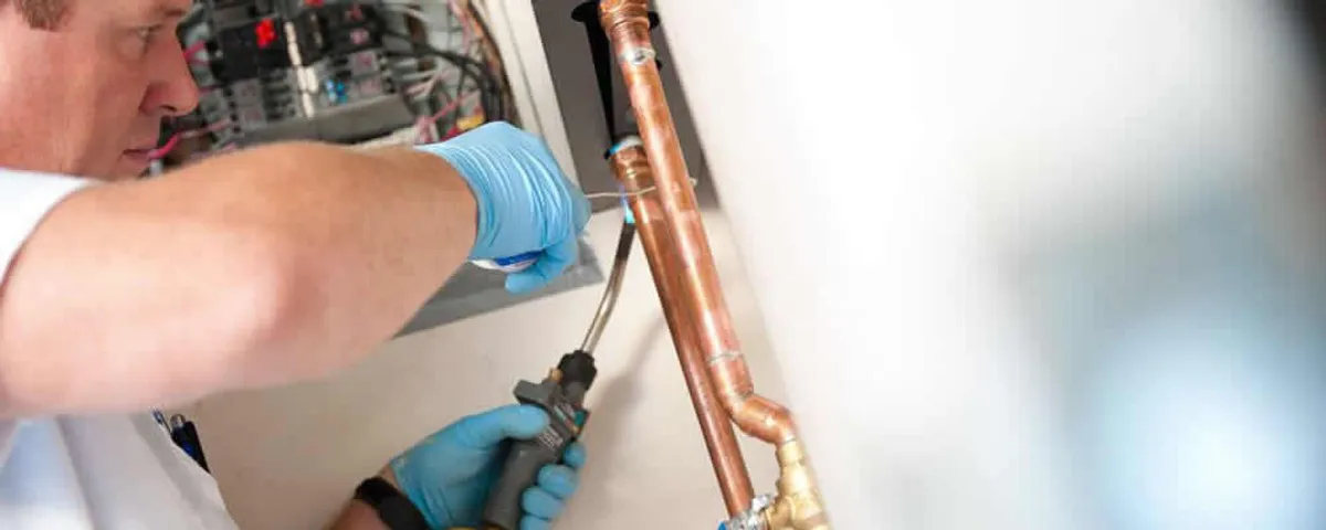 Water heater repair technician testing copper pipe connections and controls in Allen, TX